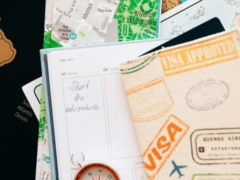 Flat lay of travel essentials including compass, notebook, and map for a journey.